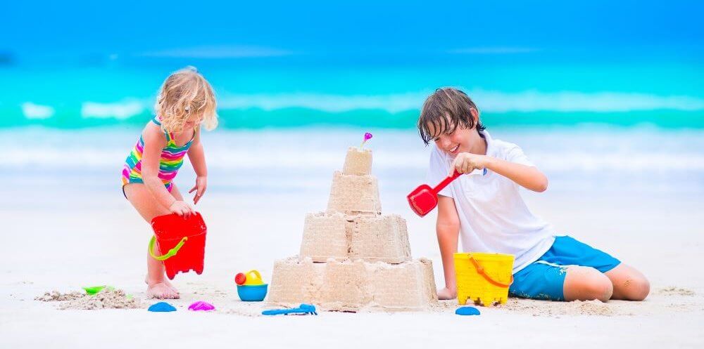 a boy and girl build a sandcastle