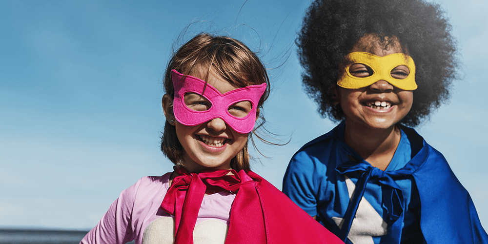 boy and girl dressed as superheroes smiling at the camera