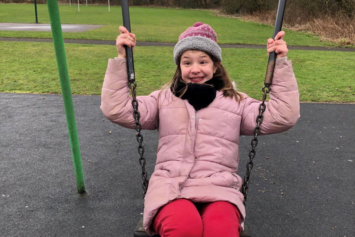 rose smiling on a set of swings