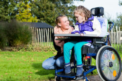 Older disabled child in wheelchair with mother.