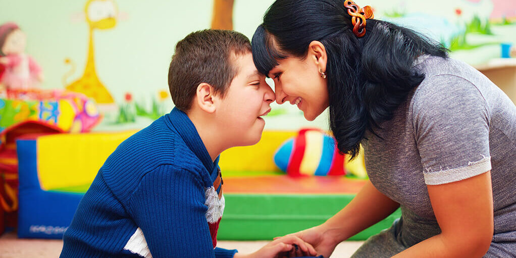 Boy with a female carer, smiling.