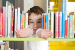 Little boy looking through books, borrow ebooks from Cerebra.
