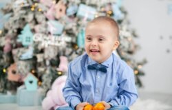 a little boy sat in front of a snowy christmas tree