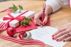 a woman's hands writing a christmas card